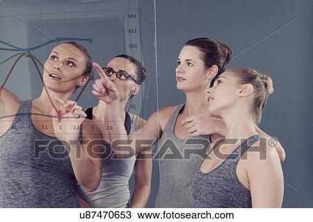 Young women pointing at chart on glass wall, grey background View Large Photo Image Stock Image - Young women pointing at chart on glass wall, grey background. Fotosearch