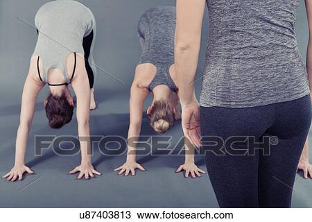 Stock Image - Young women practising yoga, grey background. Fotosearch