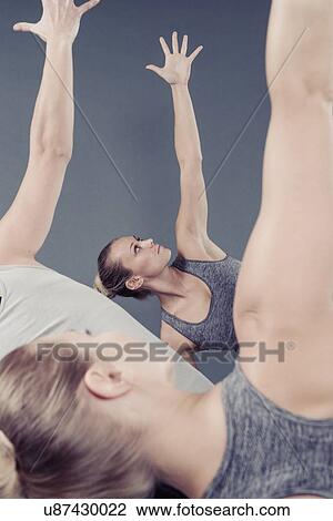 Stock Image - Young women practising yoga, grey background. Fotosearch