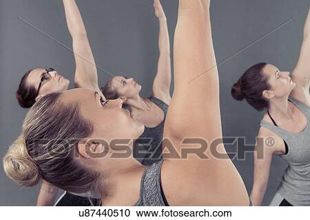 Stock Image - Young women practising yoga, grey background. Fotosearch