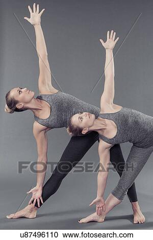 Stock Image - Young women practising yoga, grey background. Fotosearch