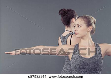 Stock Image - Young women practising yoga, grey background. Fotosearch