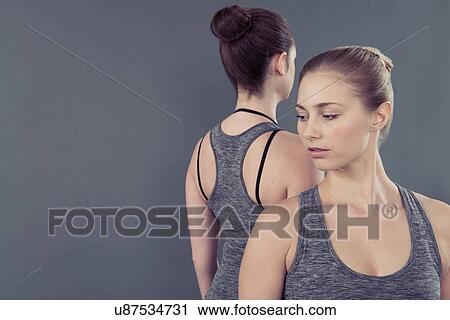 Stock Image - Young women practising yoga, grey background. Fotosearch