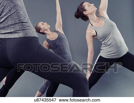 Stock Photo - Young women practising yoga, grey background. Fotosearch