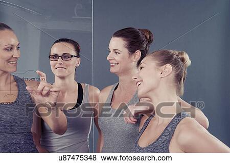 Young women studying chart on glass wall, grey background View Large Photo Image Stock Photo - Young women studying chart on glass wall, grey background. Fotosearch