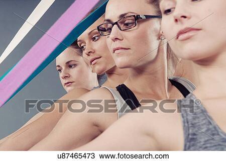 Stock Image - Young women using coloured bands, grey background. Fotosearch