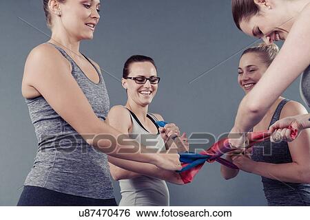 Young women using coloured bands, grey background View Large Photo Image Stock Photograph - Young women using coloured bands, grey background. Fotosearch