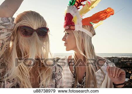 Stock Photo - Young women wearing feather headdress and sunglasses with hair covering face. Fotosearch