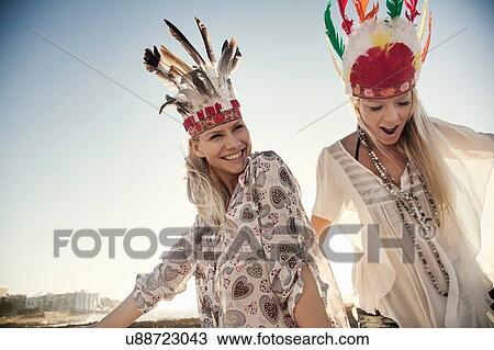 Young women wearing feather headdresses dancing in sunlight, looking at camera smiling View Large Photo Image Stock Image - Young women wearing feather headdresses dancing in sunlight, looking at camera smiling. Fotosearch