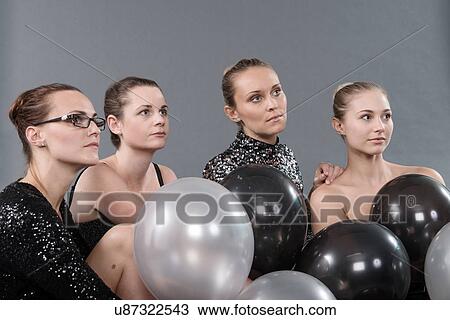 Stock Image - Young women with black and white balloons, grey background. Fotosearch