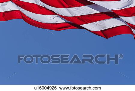 Stock Photograph - American flag against blue sky. Fotosearch