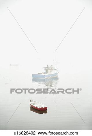 Stock Image - Boats in fog floating on water. Fotosearch