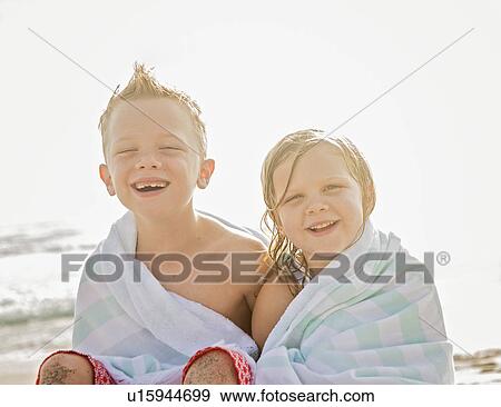 Boy (6-7) and girl (4-5) sitting on beach wrapped in towels View Large Photo Image Stock Photo - Boy (6-7) and girl (4-5) sitting on beach wrapped in towels. Fotosearch
