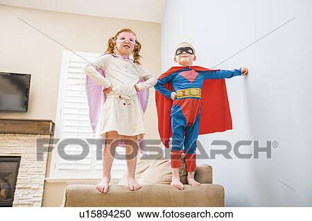 Stock Image - Children (2-3, 4-5) playing superhero on sofa. Fotosearch
