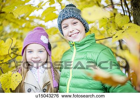 Stock Photograph - Children standing besides autumn plants. Fotosearch