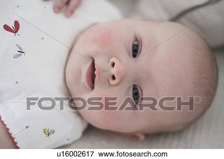 Stock Photo - Cute baby girl (2-5 months) lying on bed. Fotosearch