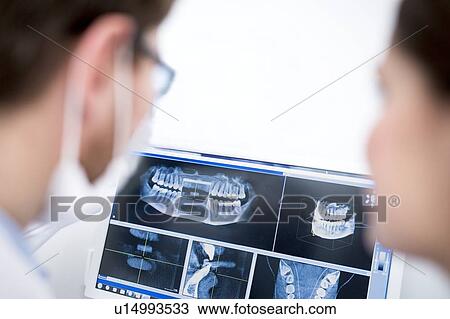 Stock Image - Dentist examining x-ray. Fotosearch