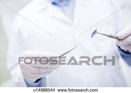 Picture - Dentist holding dental equipment. Fotosearch
