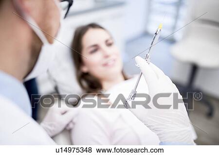 Stock Photo - Dentist holding syringe. Fotosearch
