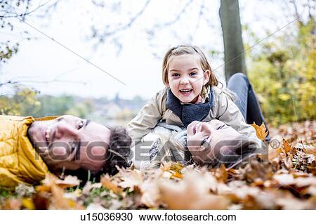 Family lying on dried leaves View Large Photo Image Stock Image - Family lying on dried leaves. Fotosearch