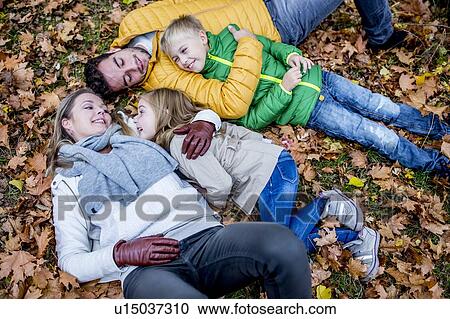 Stock Image - Family lying on dried leaves. Fotosearch