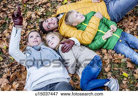 Stock Photo - Family lying on dried leaves. Fotosearch