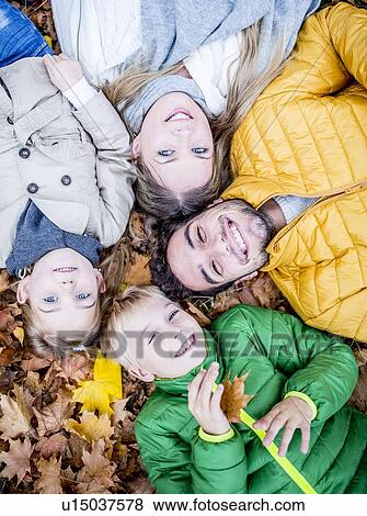 Stock Photo - Family lying on dried leaves. Fotosearch