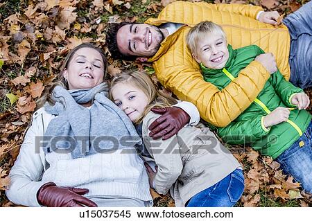 Stock Photography - Family lying on dried leaves. Fotosearch