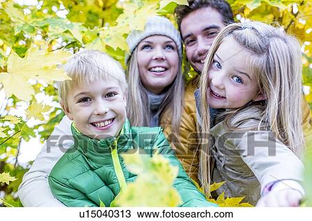 Stock Image - Family surrounded by autumn leaves. Fotosearch