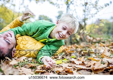 Father and son lying on dried leaves View Large Photo Image Picture - Father and son lying on dried leaves. Fotosearch