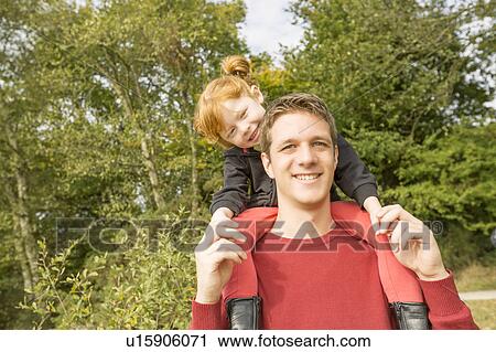 Stock Image - Father carrying on shoulders daughter (4-5). Fotosearch