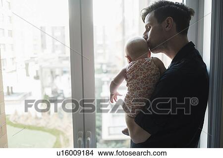 Picture - Father looking through window with daughter (2-5 months). Fotosearch