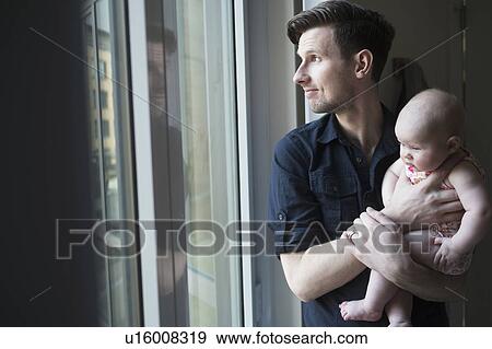 Stock Photo - Father looking through window with daughter (2-5 months). Fotosearch