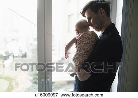 Stock Photo - Father looking through window with daughter (2-5 months). Fotosearch