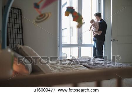Stock Photo - Father looking through window with daughter (2-5 months). Fotosearch