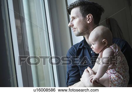 Stock Photograph - Father looking through window with daughter (2-5 months). Fotosearch