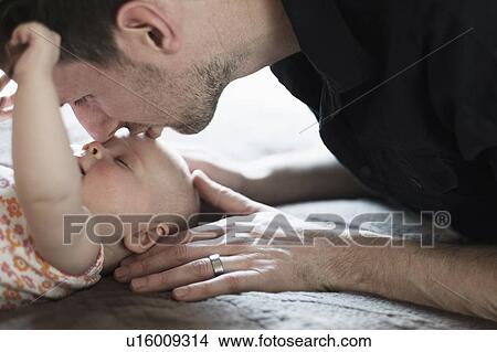 Picture - Father playing with daughter (2-5 months) on bed. Fotosearch