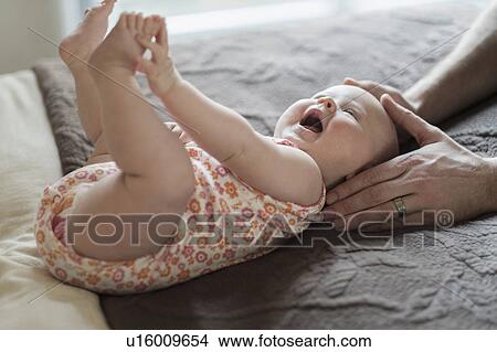 Picture - Father playing with daughter (2-5 months) on bed. Fotosearch