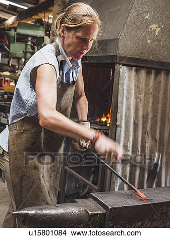Picture - Female blacksmith working in workshop. Fotosearch