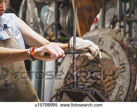 Stock Photography - Female blacksmith working in workshop. Fotosearch