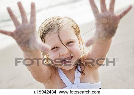Picture - Girl (4-5) on beach showing her dirty hands. Fotosearch