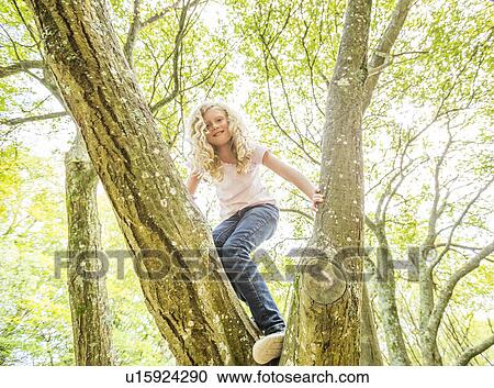 Stock Image - Girl (8-9) climbing tree. Fotosearch
