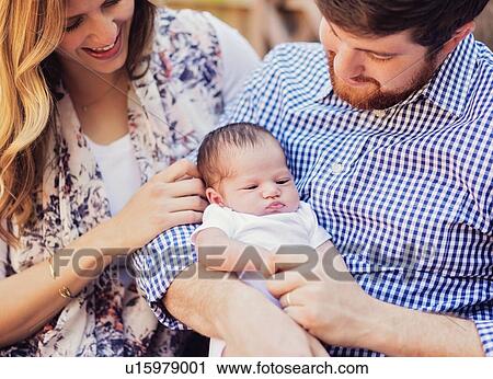 Stock Image - Happy parents holding girl (2-5 months). Fotosearch