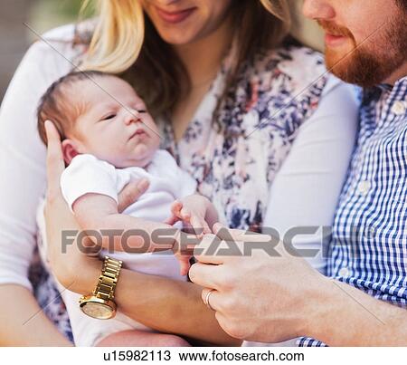 Stock Image - Happy parents holding girl (2-5 months). Fotosearch
