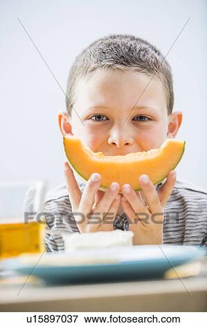 Little boy (6-7) eating cantaloupe for breakfast View Large Photo Image Stock Photo - Little boy (6-7) eating cantaloupe for breakfast. Fotosearch