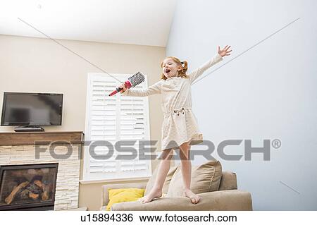 Little girl (4-5) singing into hairbrush on sofa View Large Photo Image Stock Photograph - Little girl (4-5) singing into hairbrush on sofa. Fotosearch
