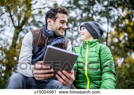 Man and boy using digital tablet View Large Photo Image Stock Image - Man and boy using digital tablet. Fotosearch