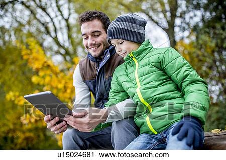 Stock Image - Man and boy using digital tablet. Fotosearch