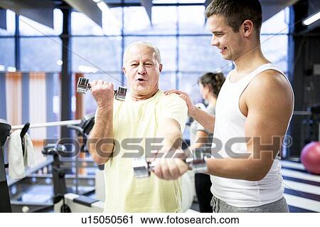 Man holding dumbbell with trainer support View Large Photo Image Stock Image - Man holding dumbbell with trainer support. Fotosearch