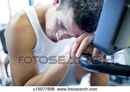 Stock Photo - Man resting his head on exercise machine. Fotosearch